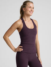 model wearing a purple racerback tank top and purple high-waisted midi length leggings.